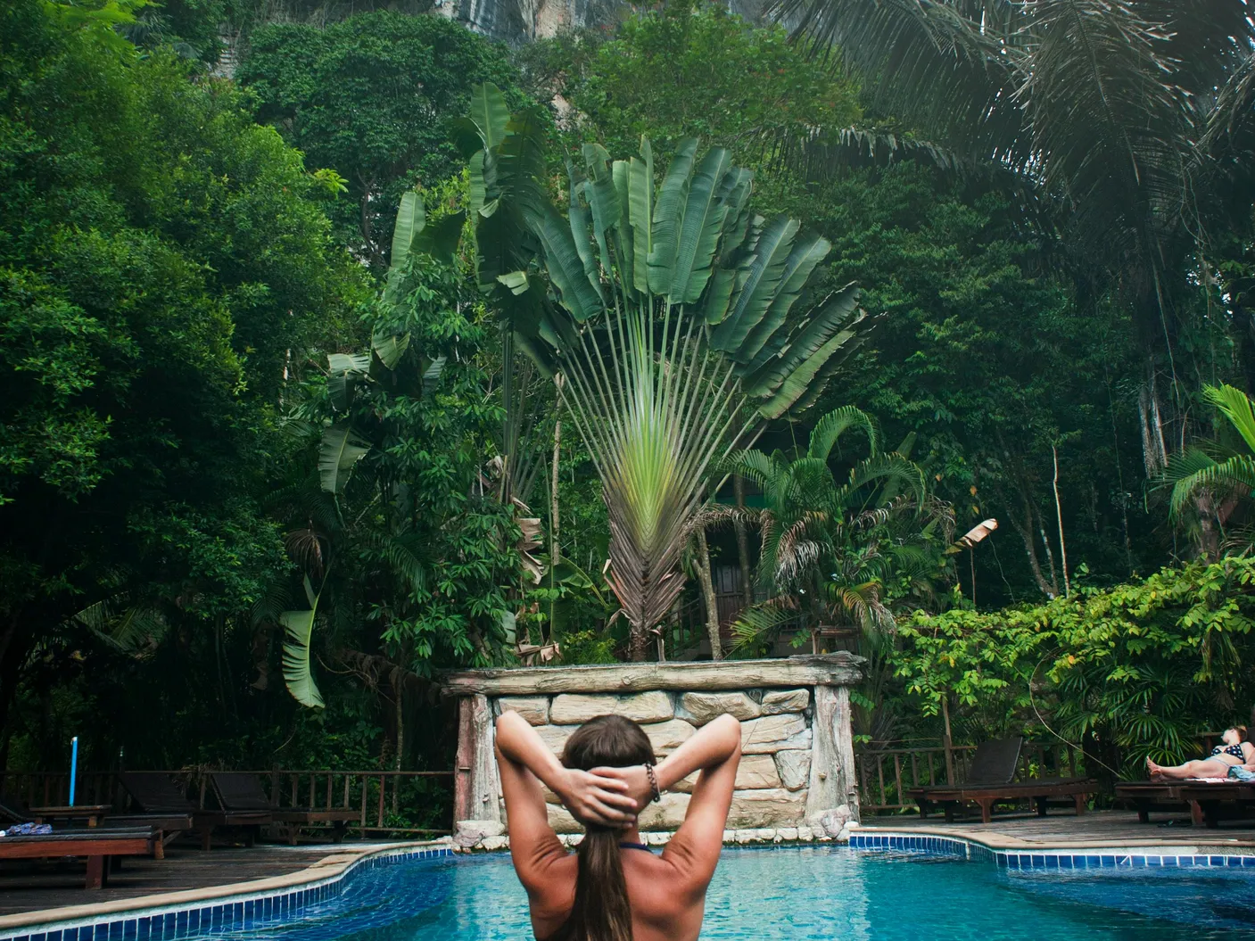 A person relaxing in a hot tub surrounded by lush greenery, illustrating the tranquility of using bromine and chlorine in hot tubs.