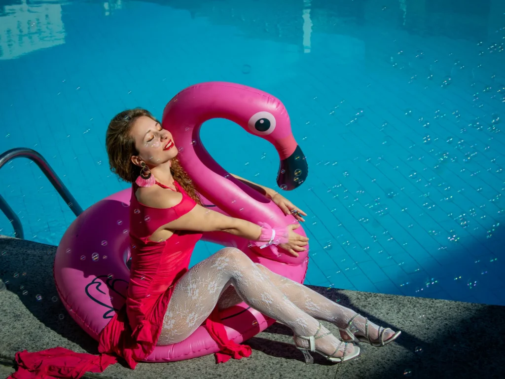 clean-glass-pool-tile.jpg-2 A woman relaxing on a pink flamingo float in a clean glass pool with sparkling tiles.