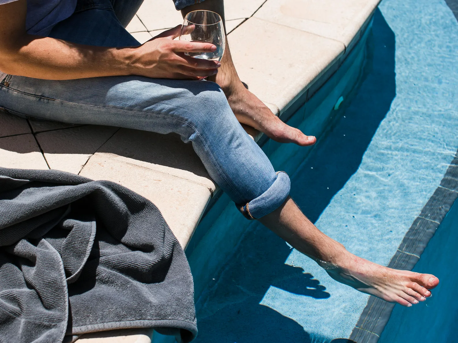 Person enjoying a drink by a commercial swimming pool, showcasing the recreational benefits of pools.