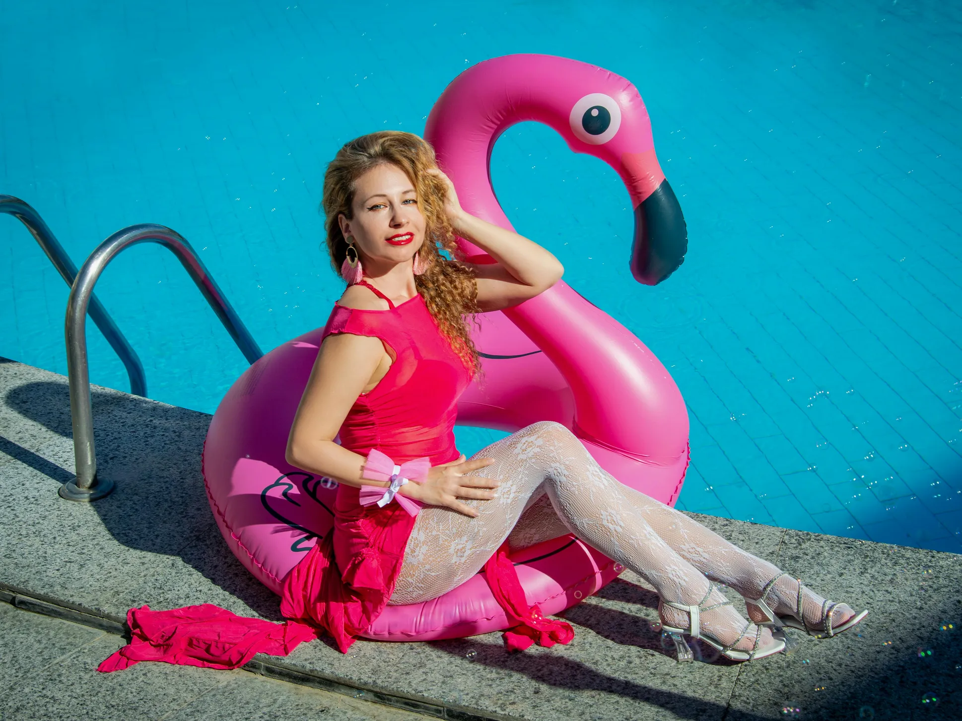 Woman by the pool enjoying a pink flamingo float, related to cyanuric acid calculator for swimming pools.
