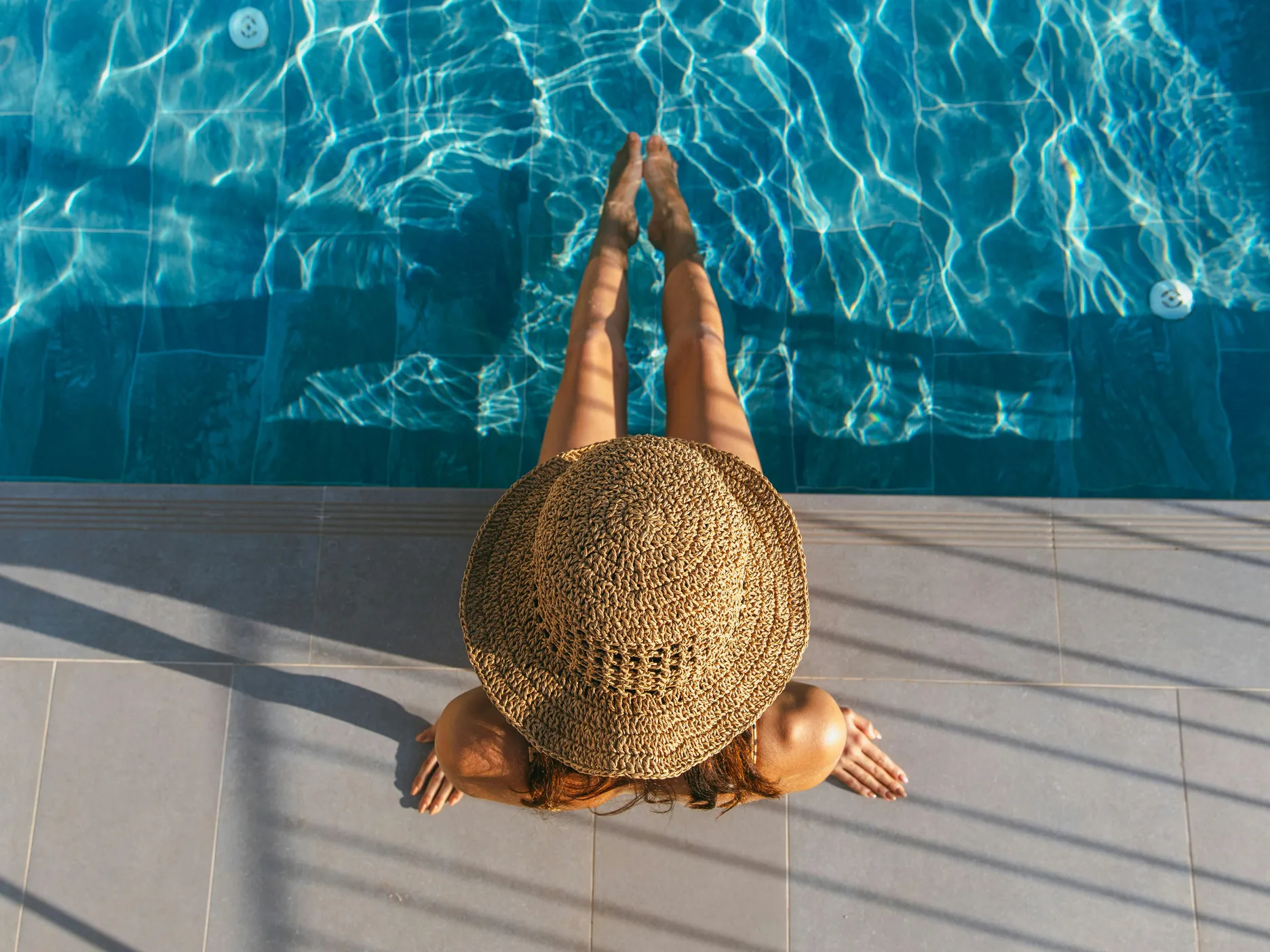 A person relaxing by a swimming pool, discussing if dogs can swim in pools and saltwater.