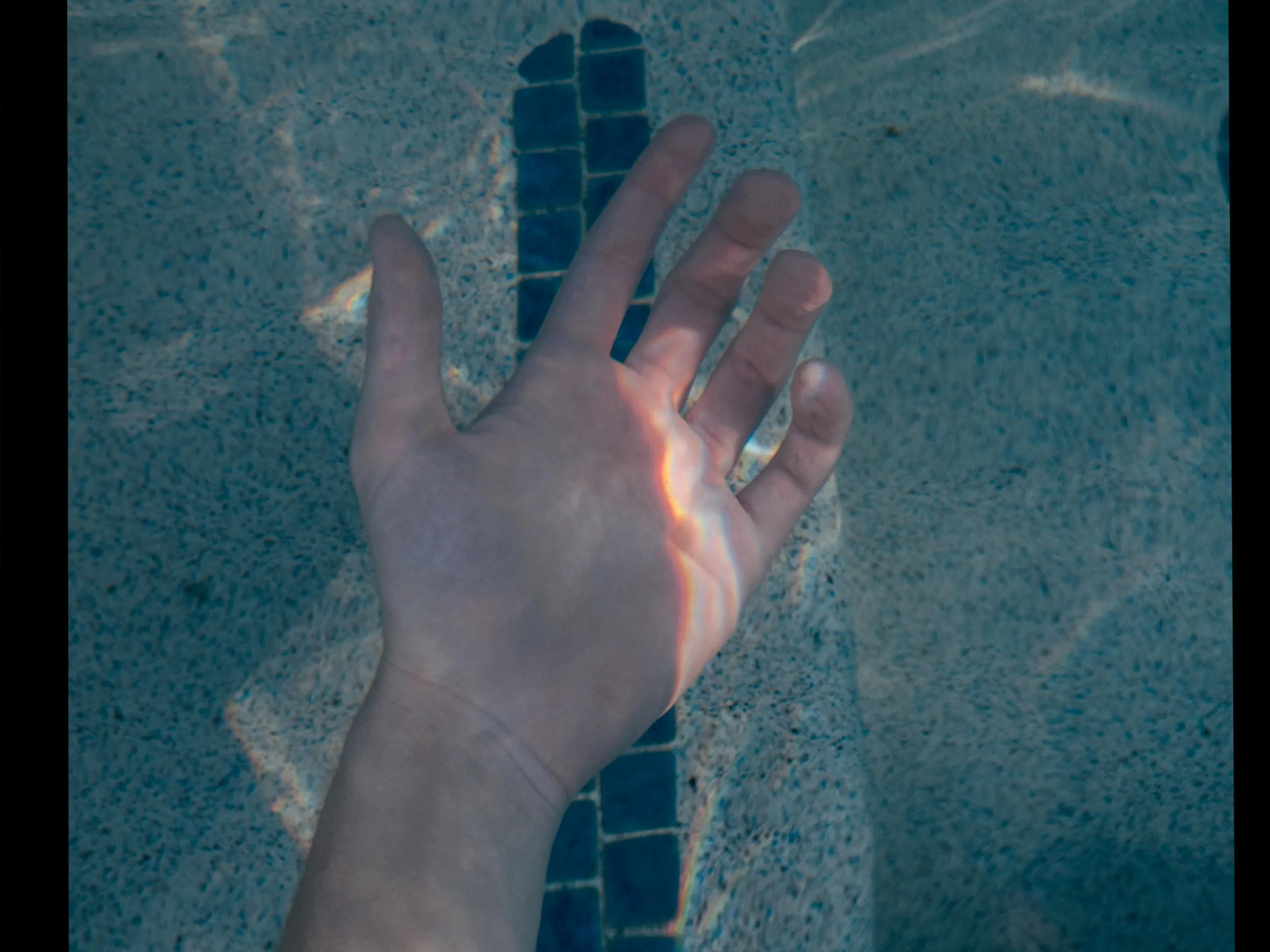 Person's hand submerged in clear pool water, illustrating the importance of proper pool chemistry and maintenance using a dry acid pool calculator.