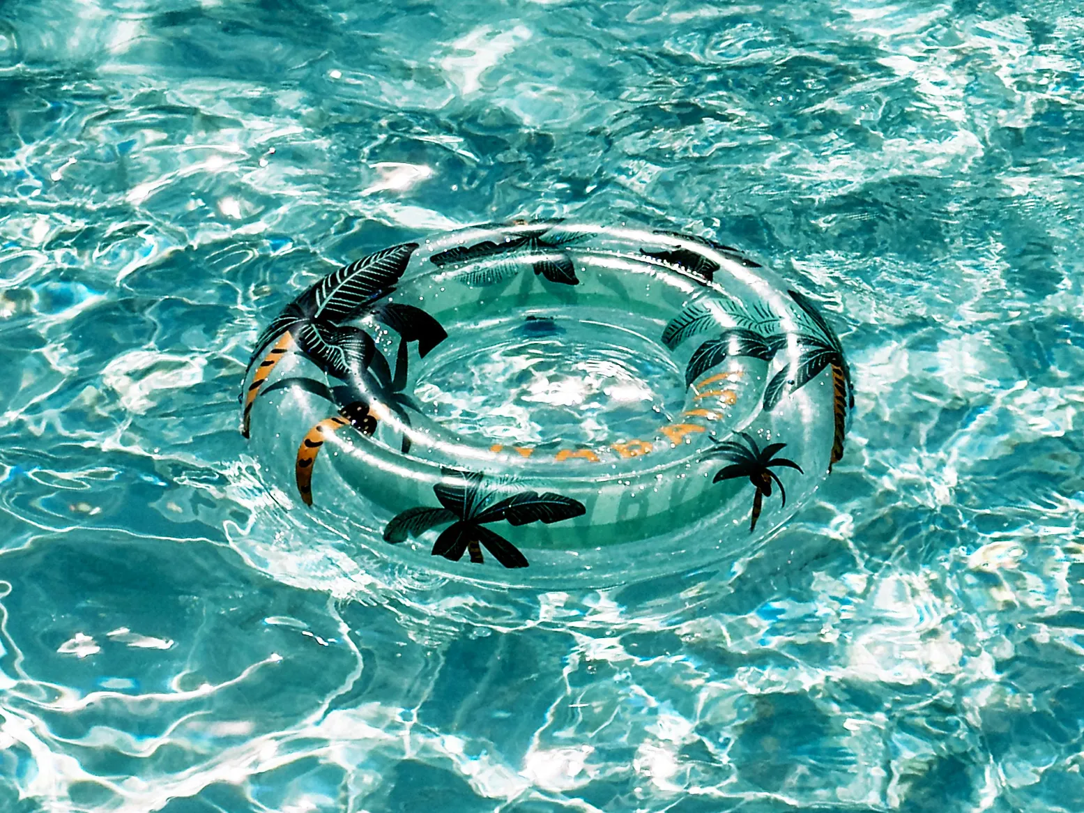 A clear inflatable pool float with palm leaf design, perfect for a duck-themed pool.