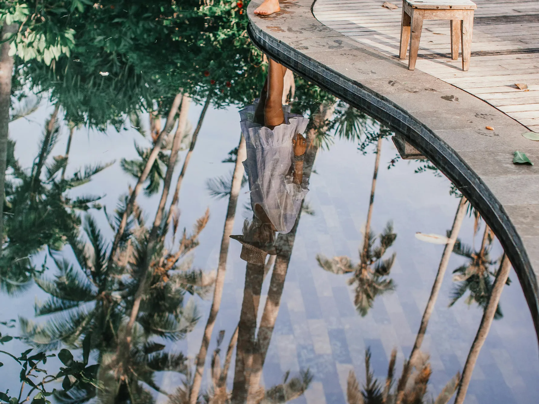 A serene swimming pool reflecting surrounding trees, illustrating the concept of dyeing pool water.