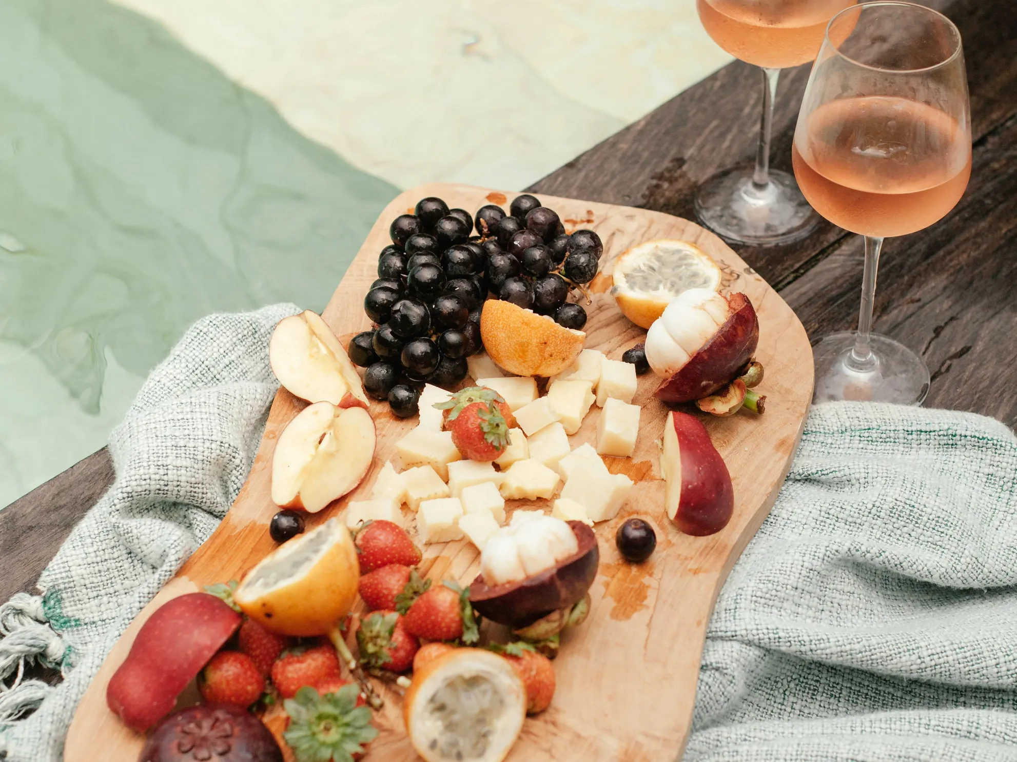 Fruit platter and wine glasses near an oval pool for relaxation and summer enjoyment