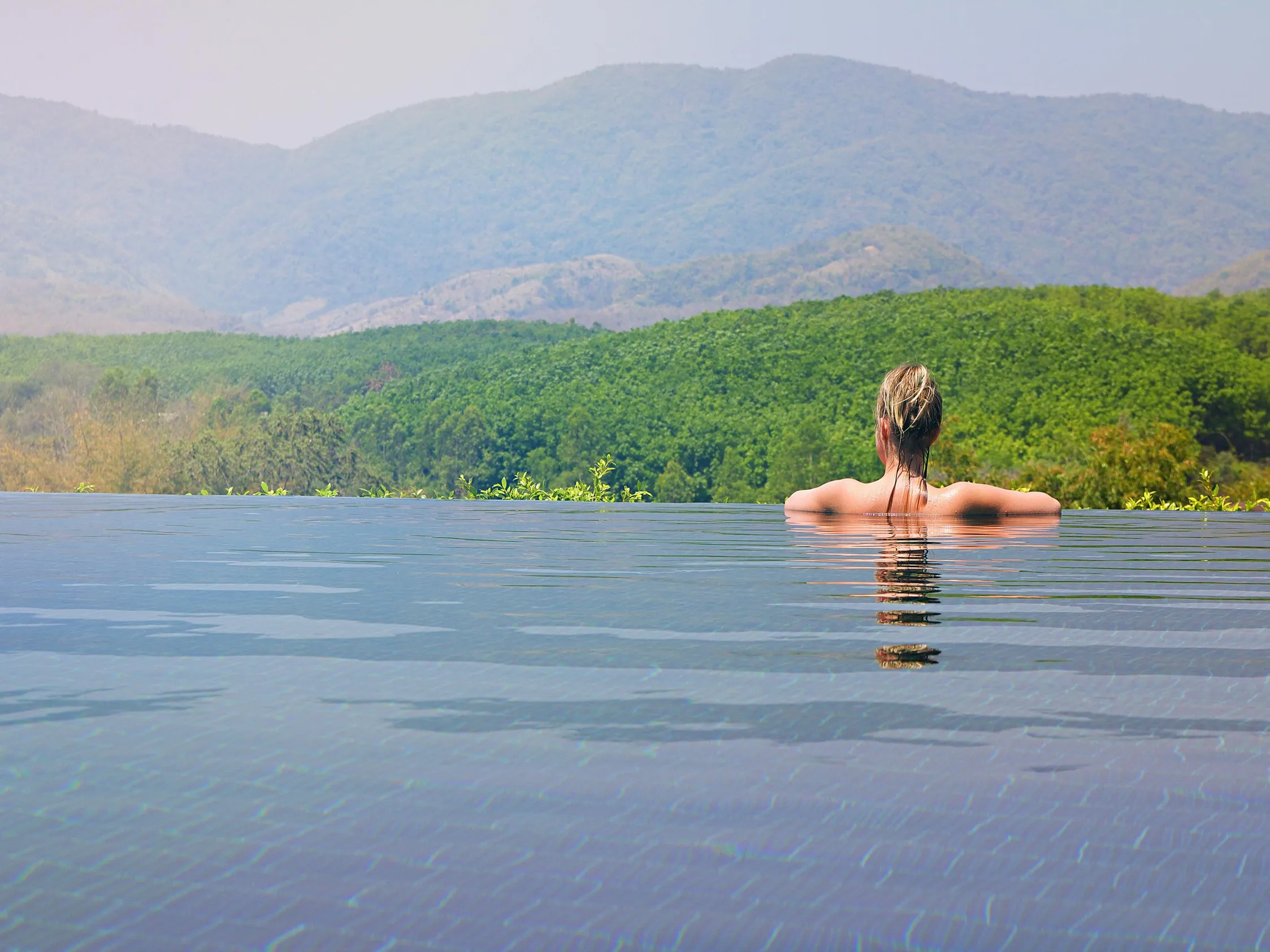 A person enjoying an infinity pool, emphasizing the importance of pool filter operation.