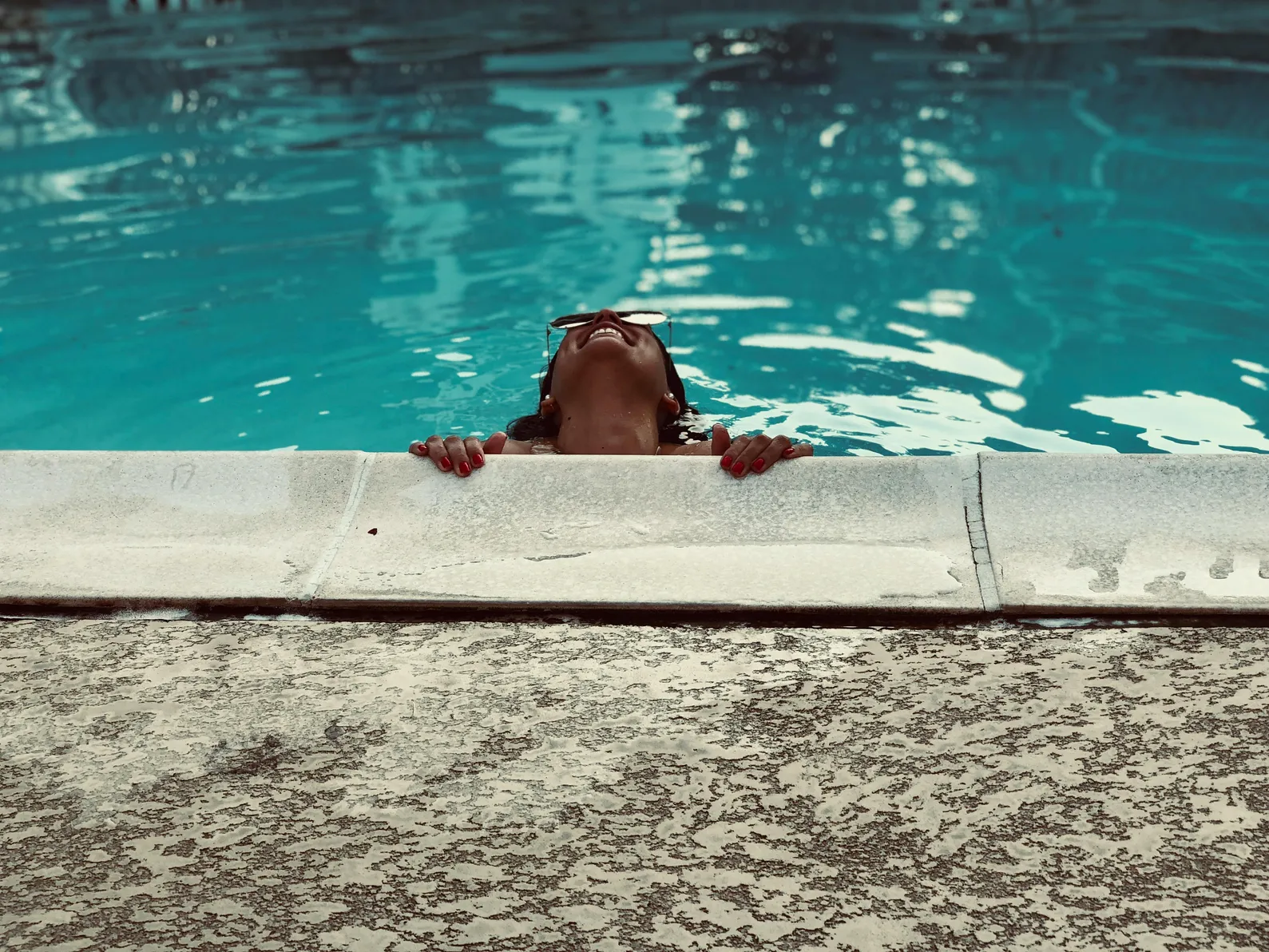 A person relaxing by a pool, illustrating the importance of pool maintenance when using a solar cover.
