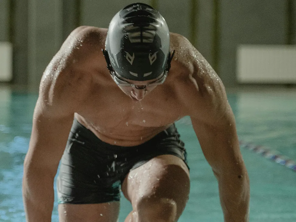 A swimmer preparing to dive into a pool, highlighting pool safety and associated materials like pool noodles.