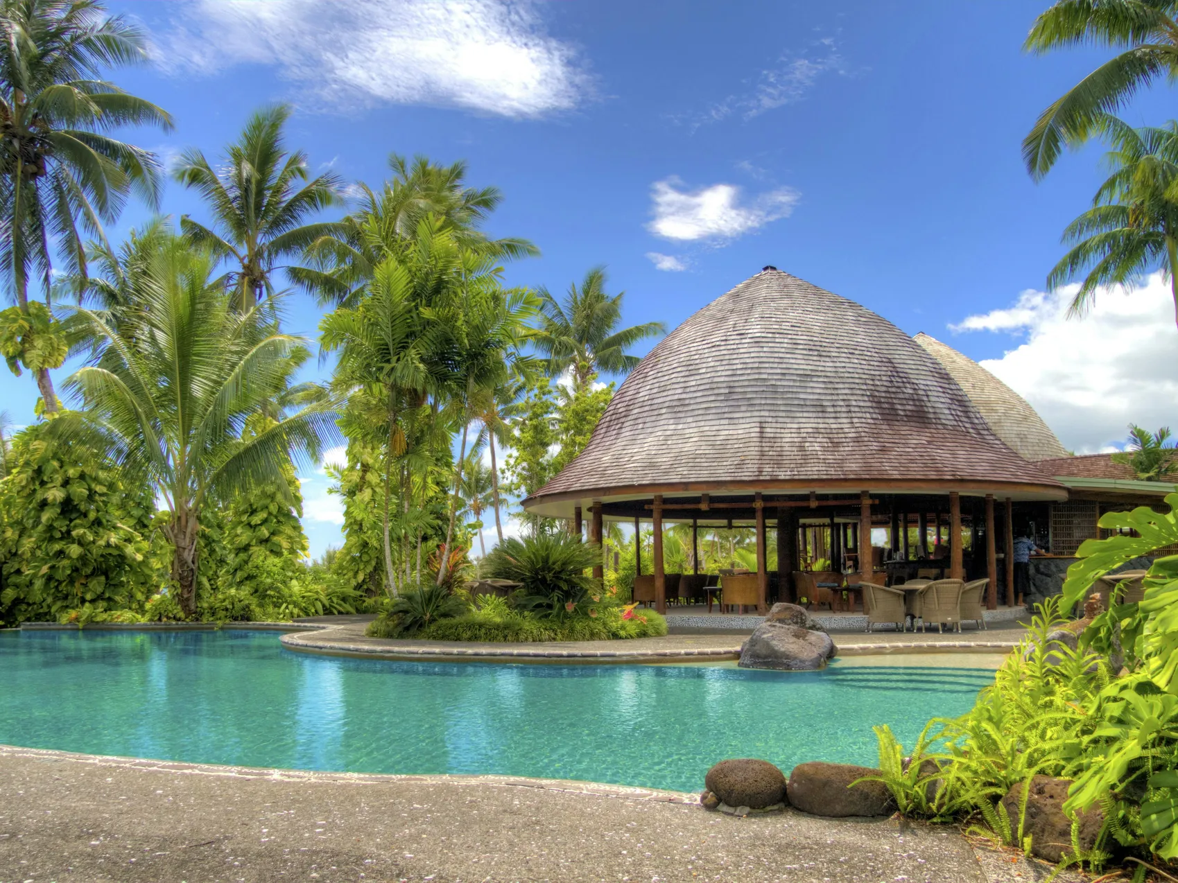 A beautiful pool in a tropical setting, highlighting the importance of calculating GPM for efficient pool pump operation.