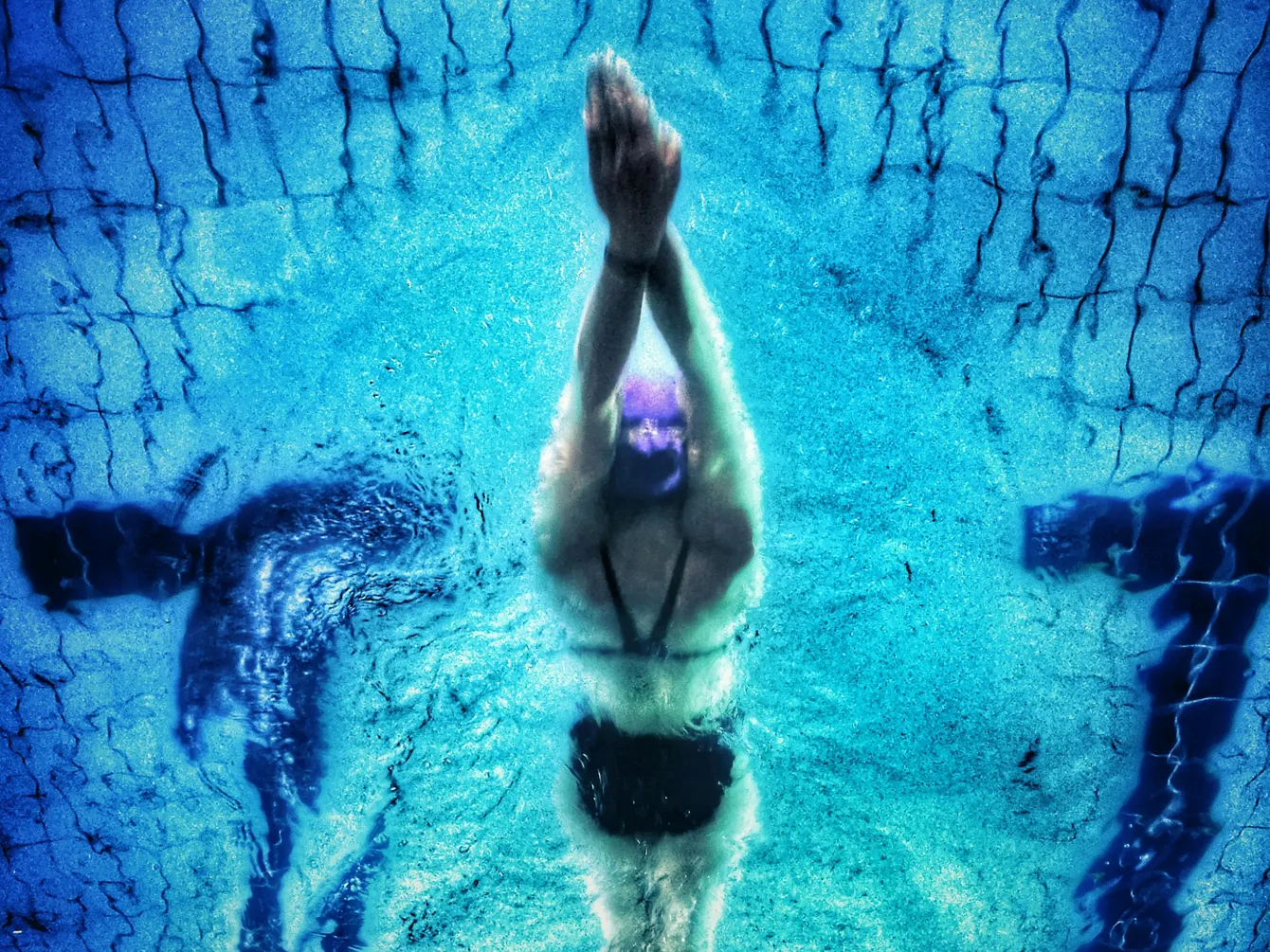 Person swimming underwater demonstrating the importance of a pool pump horsepower calculator