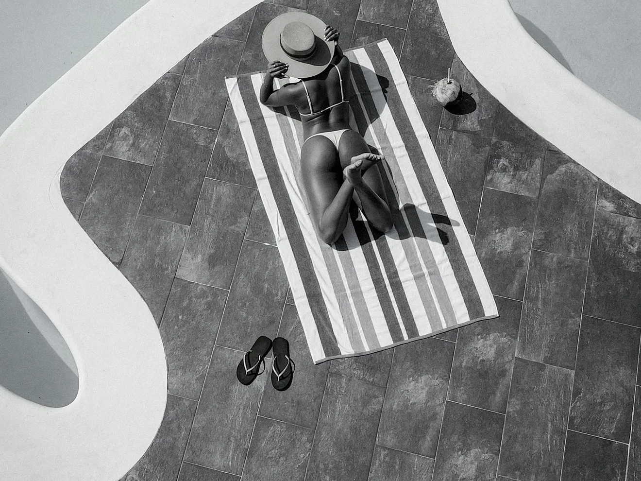 A woman laying by a pool, illustrating the relaxing environment created by a properly sized saltwater generator.