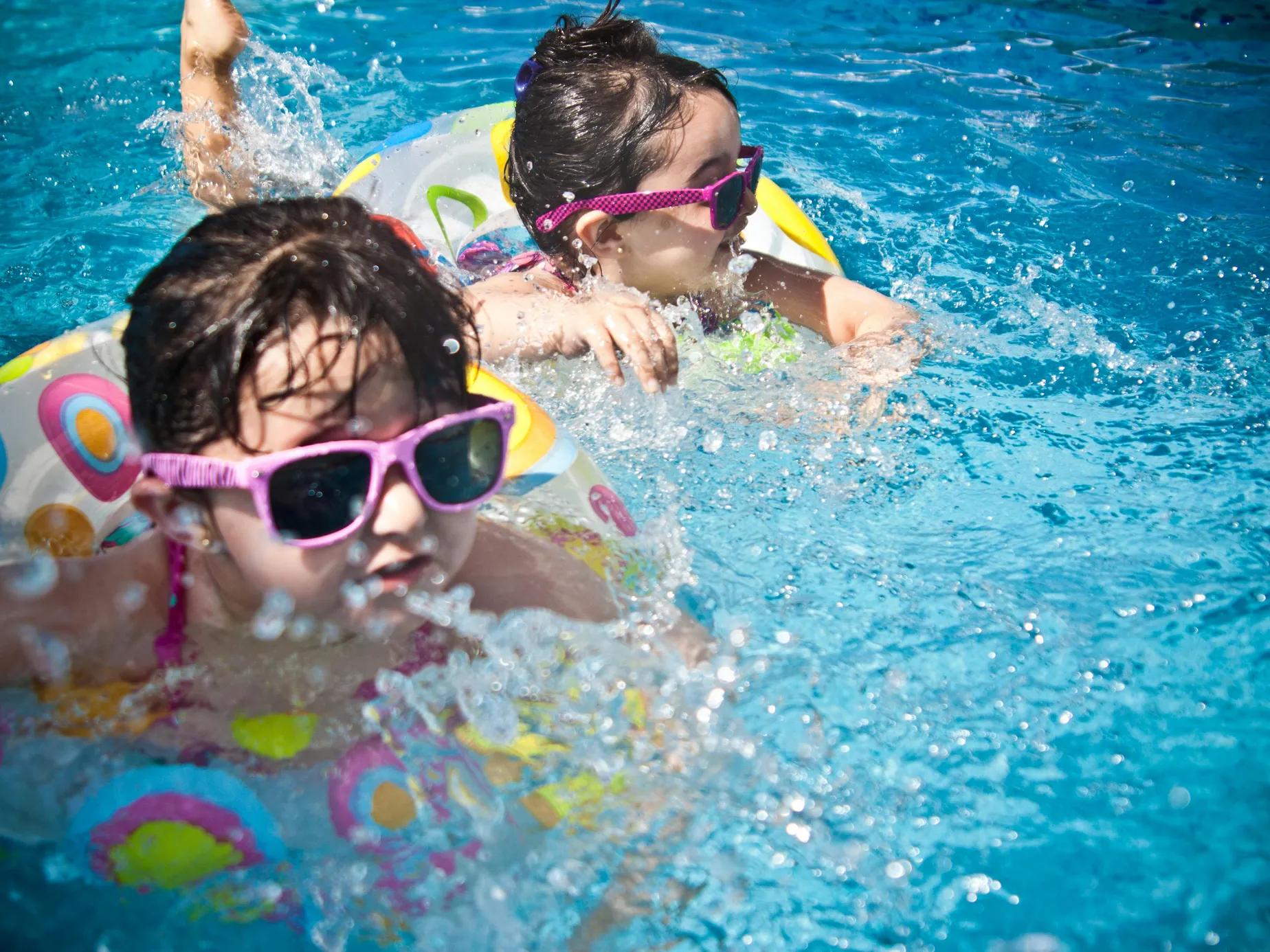 Children swimming in a pool, discussing the importance of sand under pools and the use of paver sand.