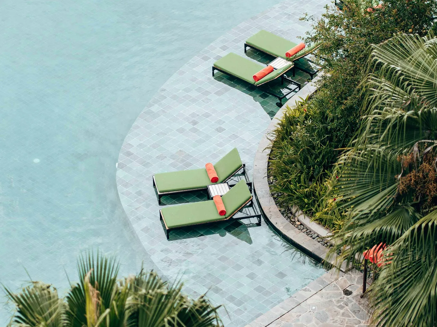 Loungers by a swimming pool, indicating a safe area to relax after adding calcium to pool water.