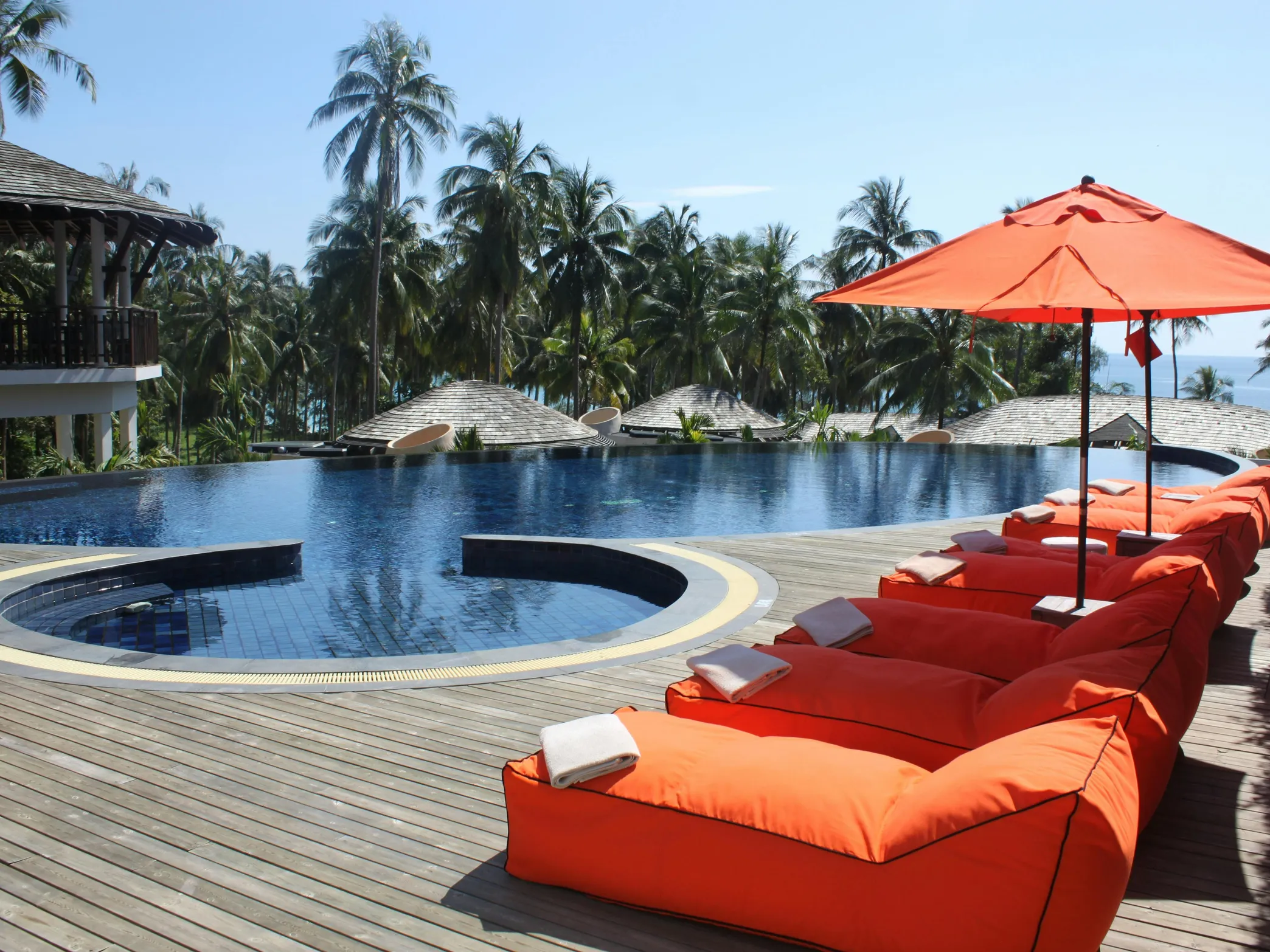 A beautiful swimming pool with bean bags and umbrellas, illustrating the importance of pool stabilizers.